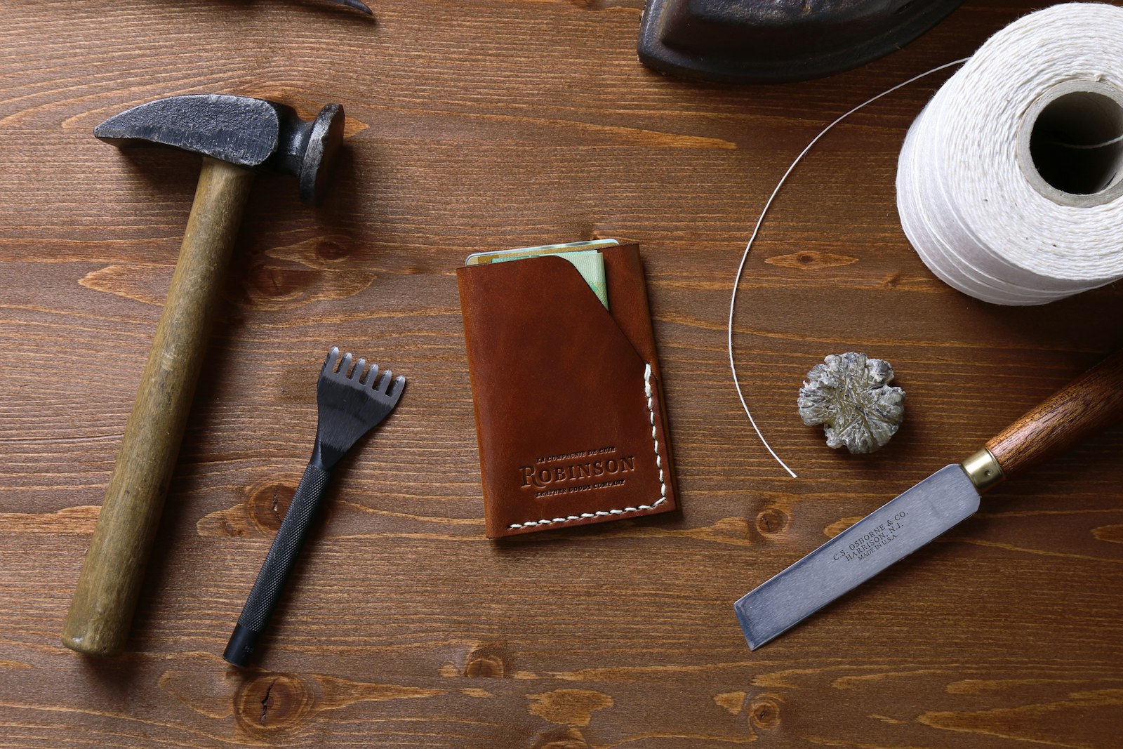 Leatherworking hand tools and a finished leather card holder on a workbench